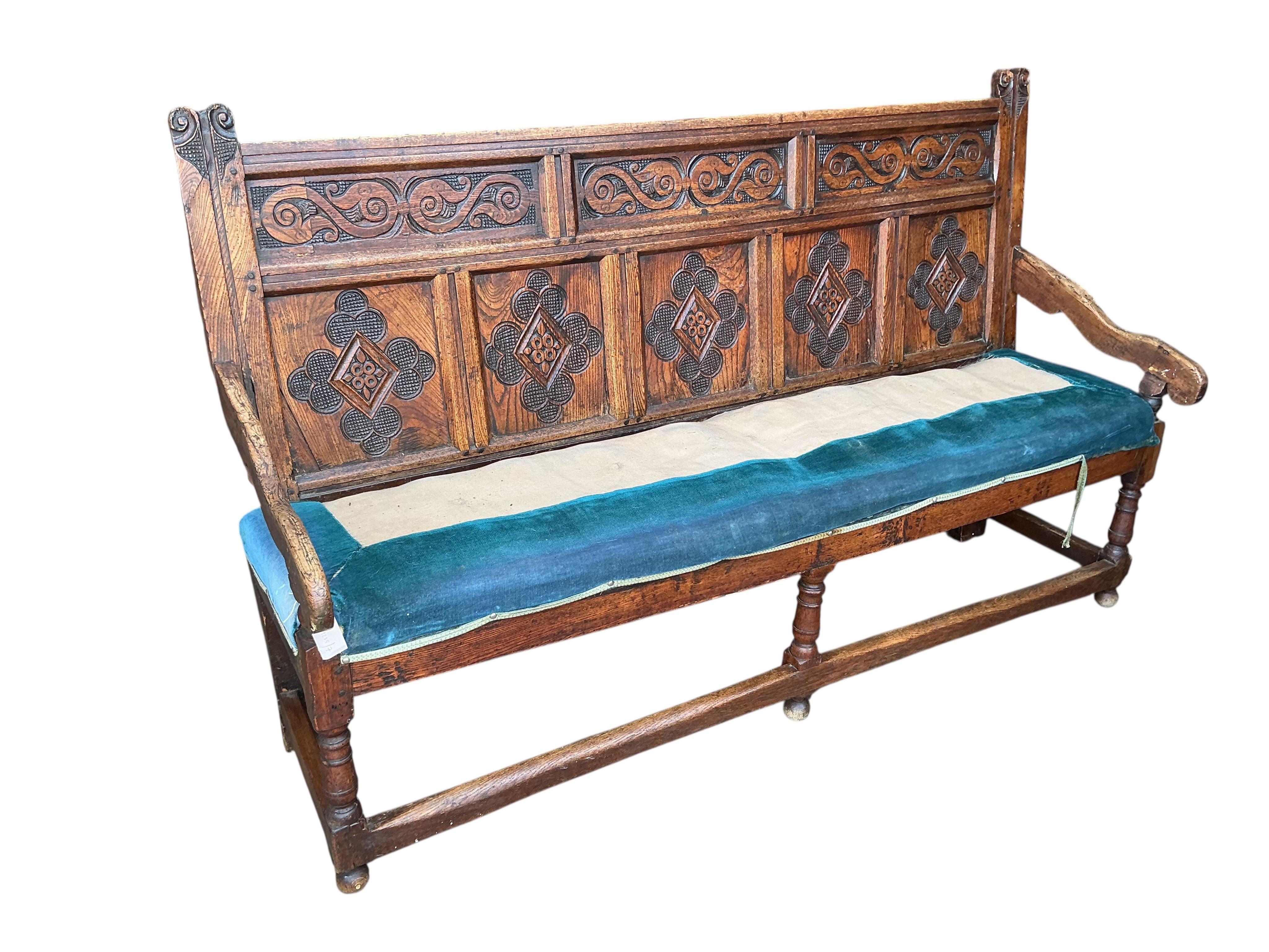 An 18th century panelled oak settle, later carved, width 177cm, depth 55cm, height 110cm